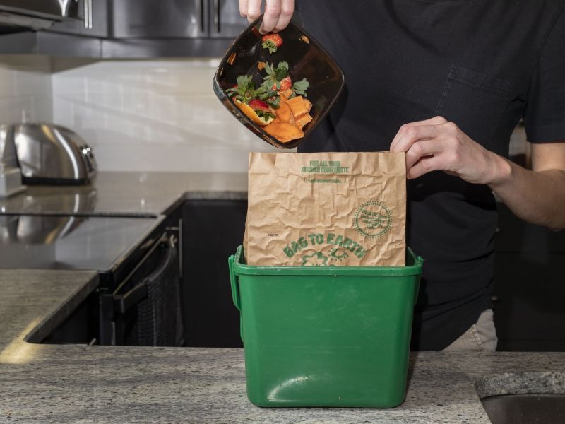 Organic materials like vegetable skins being placed in the kitchen container