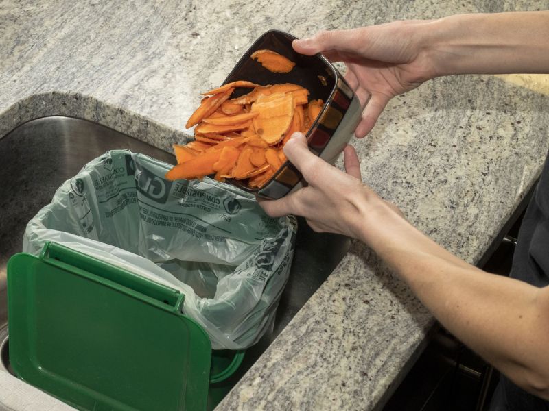 Organic materials like vegetable skins being placed in the kitchen container